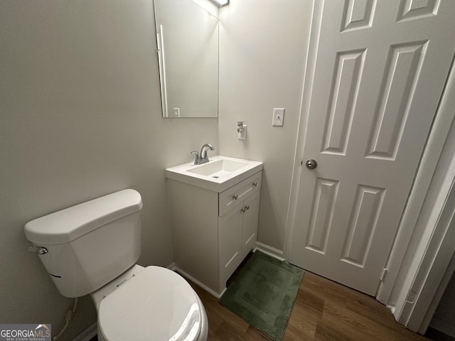 bathroom with toilet, vanity, and hardwood / wood-style flooring