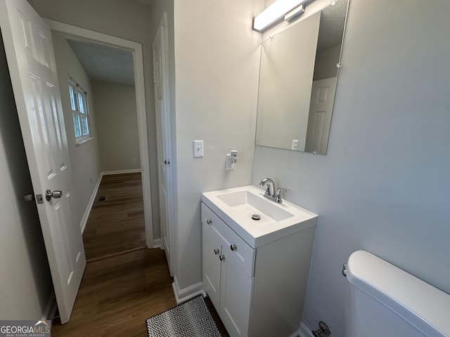 bathroom featuring toilet, hardwood / wood-style flooring, and vanity