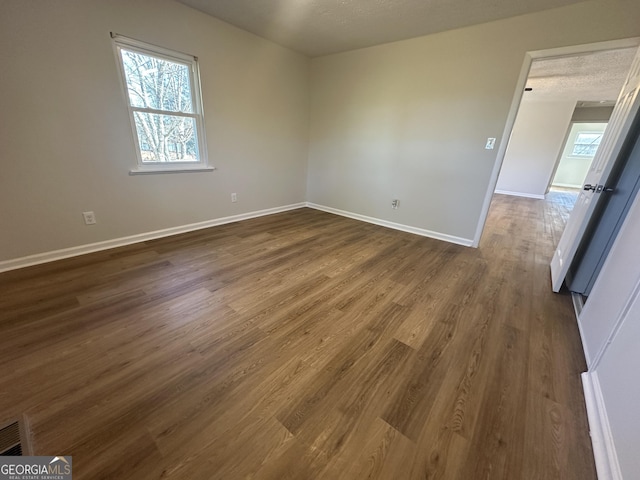 unfurnished room with a textured ceiling and dark hardwood / wood-style flooring