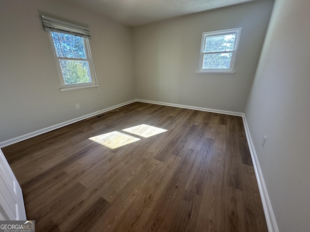 empty room featuring dark hardwood / wood-style flooring and a healthy amount of sunlight