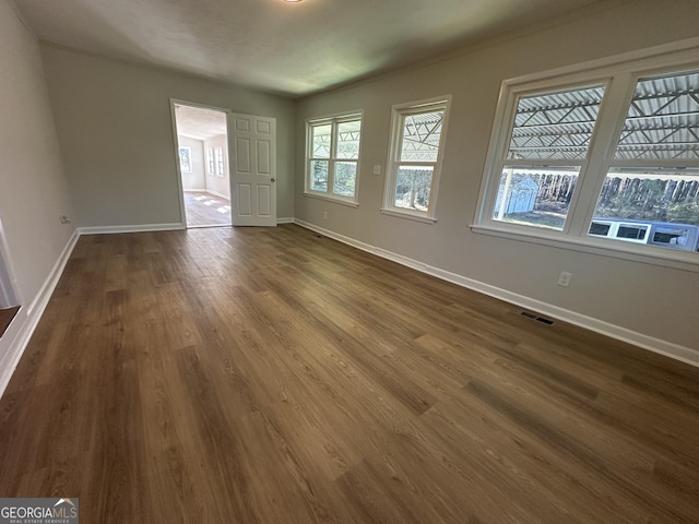 unfurnished room featuring dark wood-type flooring and a healthy amount of sunlight