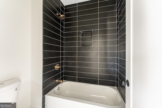 bathroom featuring toilet and tiled shower / bath