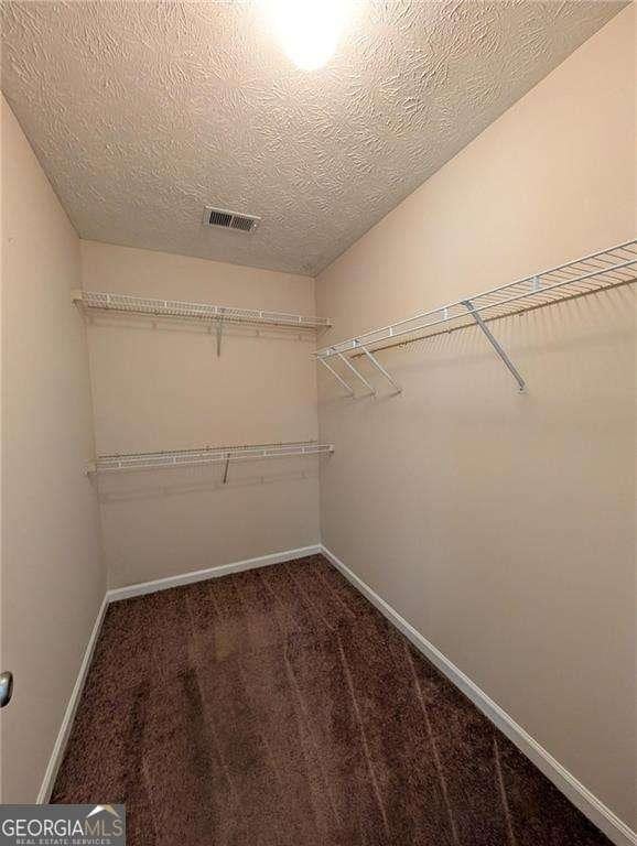 walk in closet featuring dark colored carpet