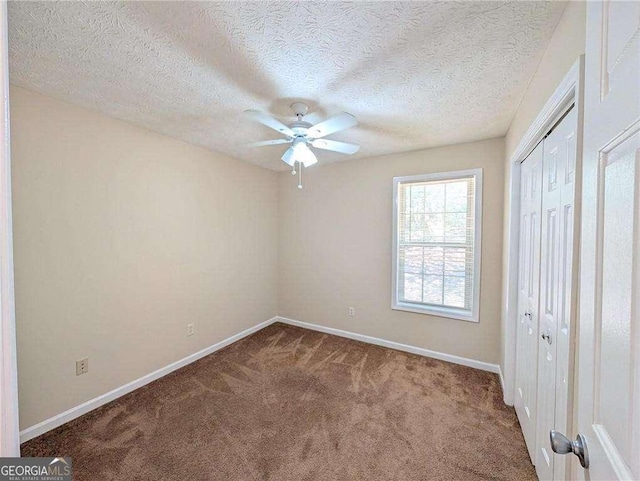 unfurnished bedroom with a textured ceiling, ceiling fan, a closet, and carpet floors