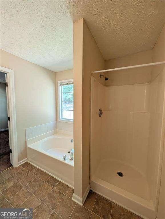 bathroom with a textured ceiling and separate shower and tub