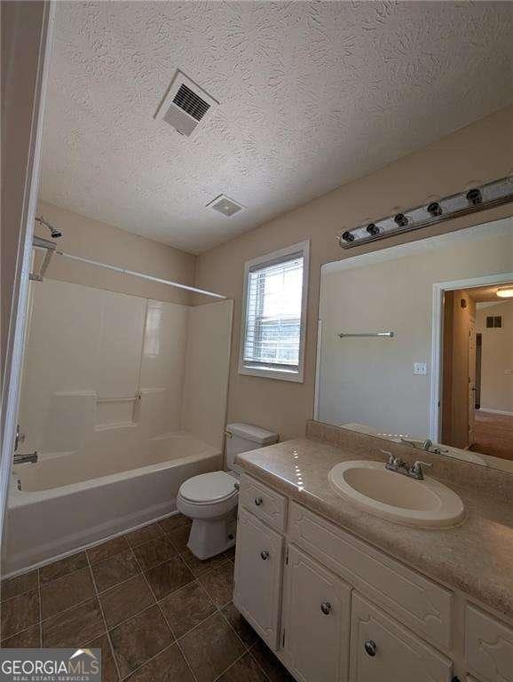 full bathroom featuring a textured ceiling, toilet, bathing tub / shower combination, and vanity