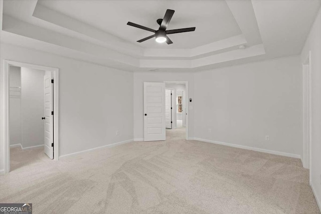 spare room featuring ceiling fan, light colored carpet, and a tray ceiling