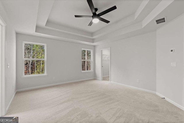 unfurnished room featuring light carpet, ceiling fan, and a tray ceiling