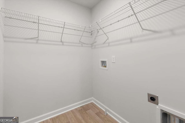 clothes washing area with wood-type flooring, washer hookup, and hookup for an electric dryer