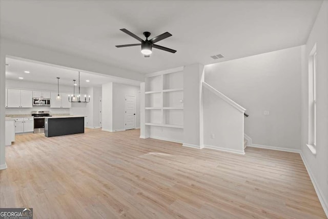 unfurnished living room featuring ceiling fan, built in features, and light wood-type flooring