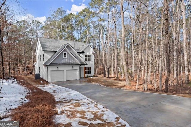 snow covered property with a garage and central AC