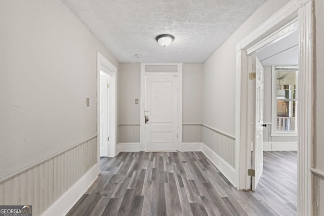 corridor with hardwood / wood-style floors and a textured ceiling