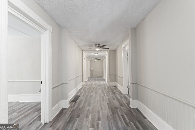 hall featuring a textured ceiling and hardwood / wood-style floors