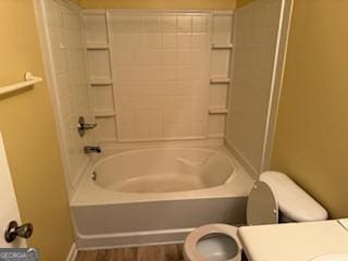 bathroom featuring toilet, wood-type flooring, and bathing tub / shower combination