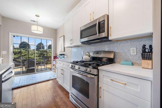 kitchen with stainless steel appliances, white cabinets, hanging light fixtures, and light stone countertops