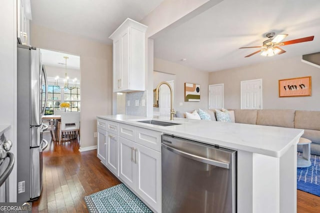 kitchen with white cabinets, appliances with stainless steel finishes, dark hardwood / wood-style flooring, sink, and kitchen peninsula