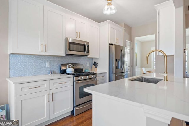 kitchen featuring light stone countertops, white cabinets, appliances with stainless steel finishes, and sink