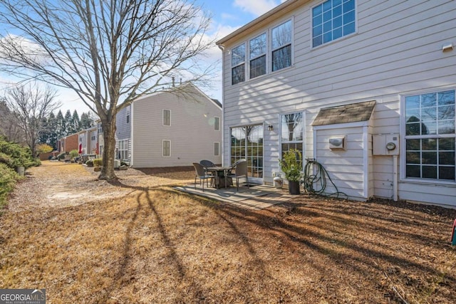 back of property with a yard and a patio