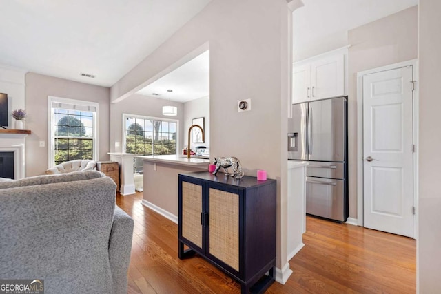 kitchen featuring stainless steel fridge with ice dispenser, white cabinetry, hardwood / wood-style flooring, and sink