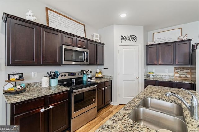 kitchen featuring light stone countertops, sink, dark brown cabinetry, and appliances with stainless steel finishes