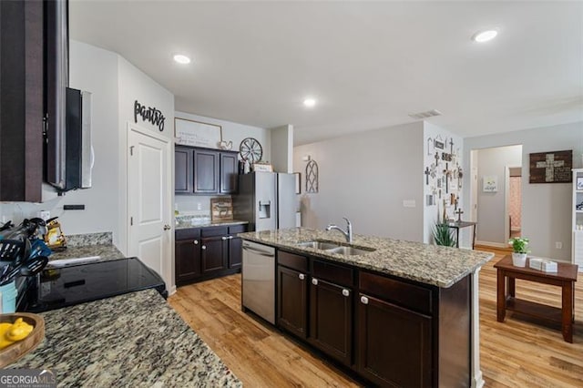 kitchen featuring sink, light hardwood / wood-style flooring, light stone countertops, an island with sink, and stainless steel appliances