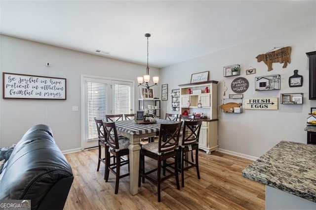 dining space featuring light hardwood / wood-style flooring and an inviting chandelier