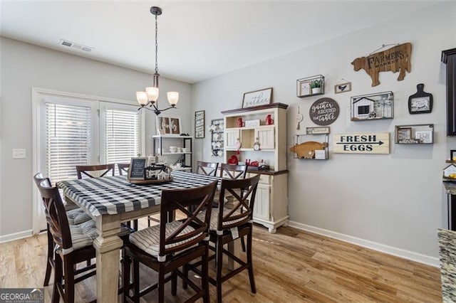 dining room with hardwood / wood-style floors and a chandelier