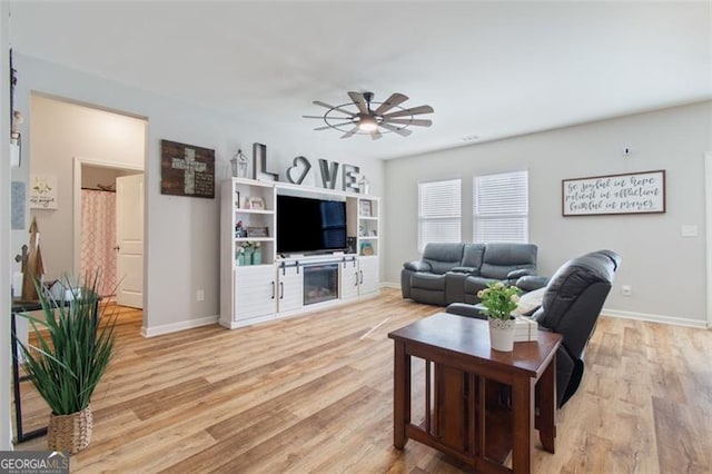 living room featuring ceiling fan, a fireplace, and light hardwood / wood-style flooring