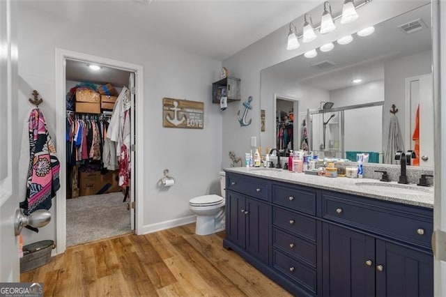 bathroom featuring hardwood / wood-style floors, toilet, a shower with door, and vanity