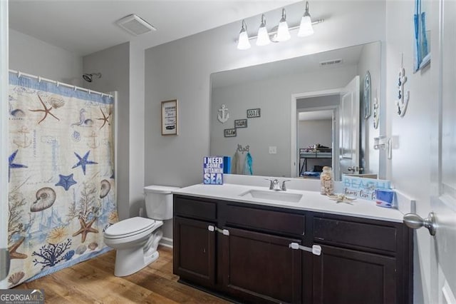 bathroom with hardwood / wood-style floors, toilet, vanity, and walk in shower