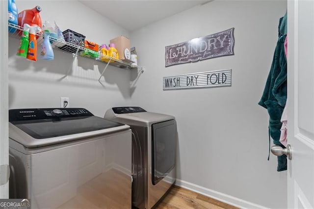 clothes washing area with washer and clothes dryer and light wood-type flooring