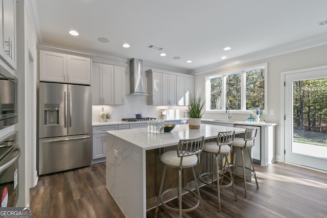 kitchen featuring a center island, sink, dark wood-type flooring, stainless steel appliances, and wall chimney exhaust hood