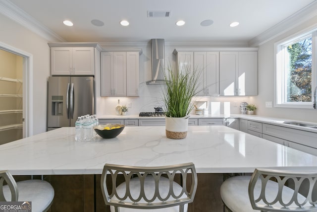 kitchen featuring crown molding, appliances with stainless steel finishes, wall chimney exhaust hood, and a center island