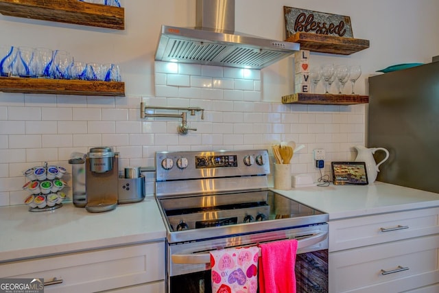 kitchen with white cabinets, exhaust hood, decorative backsplash, and stainless steel electric stove