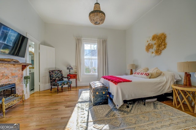 bedroom featuring hardwood / wood-style floors and a stone fireplace