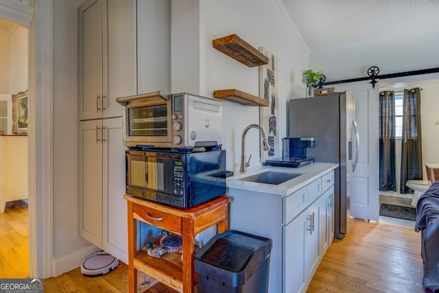 kitchen featuring light hardwood / wood-style floors, a barn door, stainless steel fridge, and sink