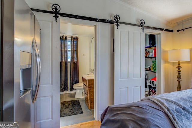 tiled bedroom featuring a barn door, stainless steel fridge, vaulted ceiling, ensuite bath, and a textured ceiling