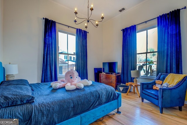 bedroom featuring crown molding, an inviting chandelier, multiple windows, and hardwood / wood-style floors