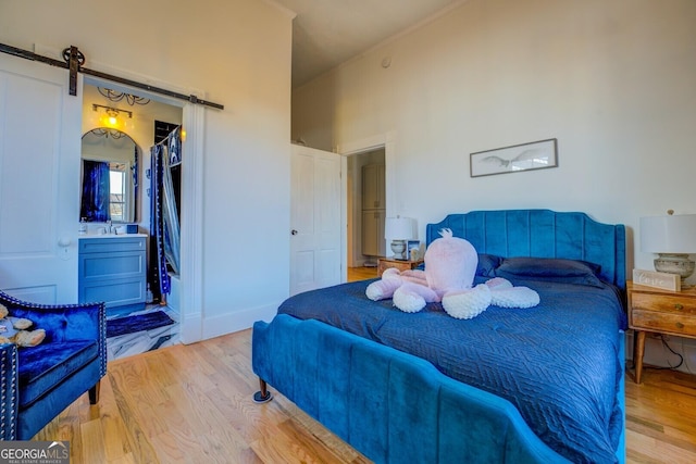 bedroom with a barn door and light wood-type flooring