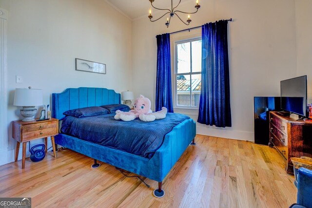 bedroom featuring crown molding, light wood-type flooring, an inviting chandelier, and lofted ceiling