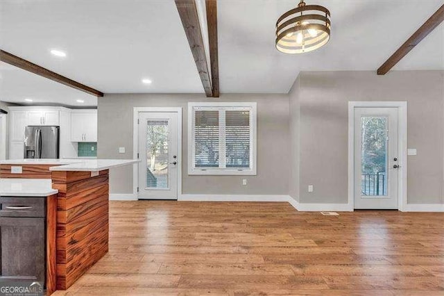 living room featuring beamed ceiling, a chandelier, and light hardwood / wood-style floors