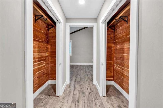 hallway featuring light wood-type flooring and wood walls