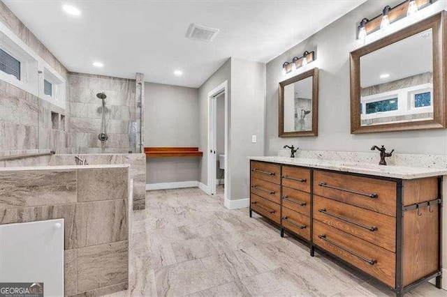 bathroom with tiled shower, vanity, and toilet