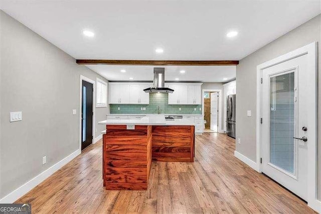 kitchen featuring exhaust hood, light hardwood / wood-style floors, backsplash, stainless steel fridge, and beam ceiling