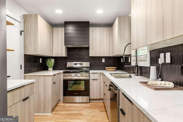 kitchen featuring light brown cabinetry, appliances with stainless steel finishes, sink, and wall chimney exhaust hood