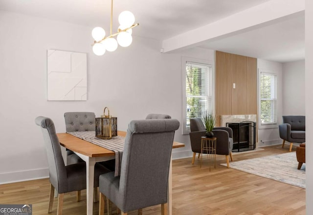 dining area with light wood-type flooring, a premium fireplace, and a chandelier