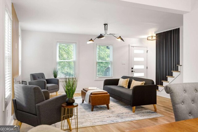 living room featuring a premium fireplace, a notable chandelier, a wealth of natural light, and light hardwood / wood-style flooring