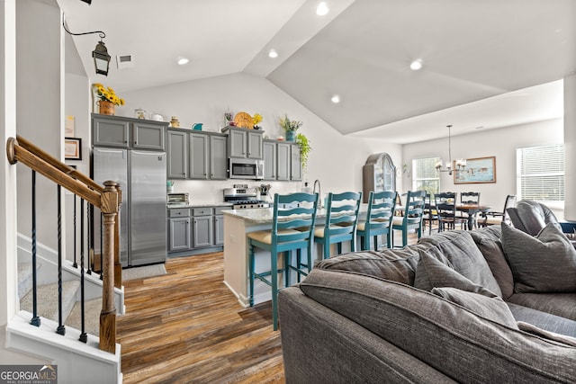 living room featuring dark wood-type flooring, lofted ceiling, and a notable chandelier