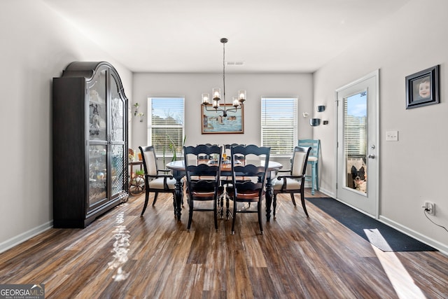 dining area featuring dark hardwood / wood-style floors and an inviting chandelier