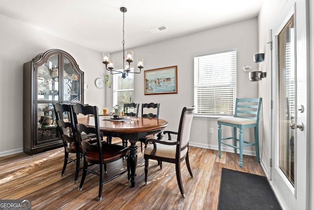 dining area featuring dark hardwood / wood-style floors and an inviting chandelier